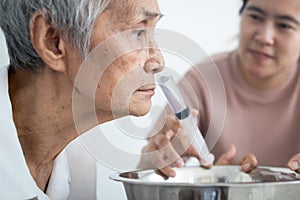 Nasal irrigation,asian caregiver is helping senior woman wash away dirt her nasal,nose cleaning,elderly people having allergic to
