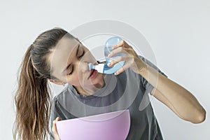 Nasal irrigation. A young girl uses the Neti Pot to treat her runny nose and colds. Nasal lavage, irrigation therapy.