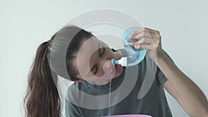 Nasal irrigation. A young girl uses the Neti Pot to treat her runny nose and colds. Nasal lavage, irrigation therapy.