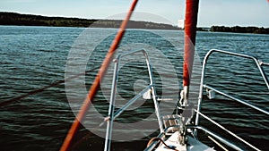 Nasal part of the sailboat goes through the waves in lake. Sailing in the wind in sunny day. Close-up view.