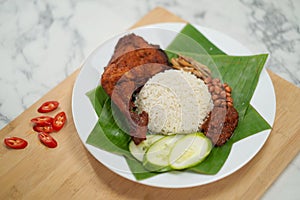 Nasi Lemak dish with chicken drum stick on marble surface on banana leaf