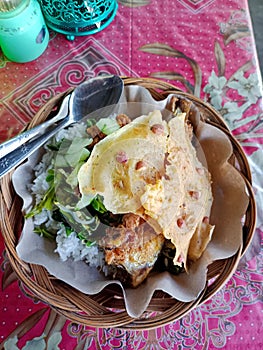 Nasi pecel from Madiun, East Java, Indonesia, consists of vegetables, peanut sauce, and fried fish.