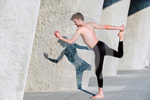 Natarajasana yoga, the posture of the Lord of the Dance practiced by a young barefoot men photo
