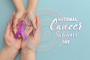 National Cancer Survivors Day. Adult and child hands holding purple ribbon on blue background. Alzheimer`s disease, Pancreatic photo