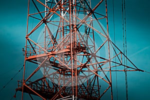 National Energy Grid system. Power pylons connecting the country. Red steel structures on deep blue sky