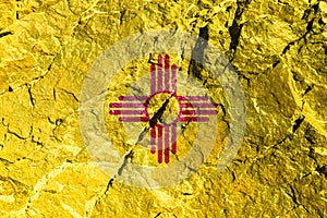 National flag of the American state of New Mexico, red sun sign, symbol of Zia, yellow for Independence Day, on a mountain wall.