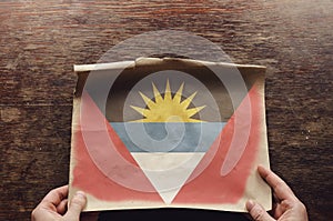 The national flag of Antigua and Barbuda on a torn piece of paper