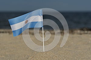National flag of Argentina on sandy shore. Red and white flag.