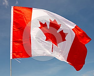 National flag of Canada flies on flagpole against blue sky