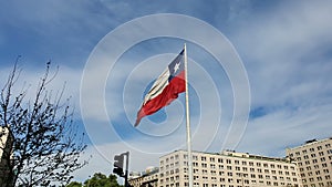 National Flag of Chile flies in a strong wind against a bright blue sky in the summer. Patriotic symbol of Chile, South America.
