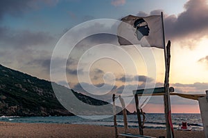 The national flag of Corsica on a beach at sunset