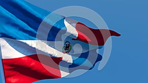 The national flag of Dominican Republic flutters in the wind against a blue sky