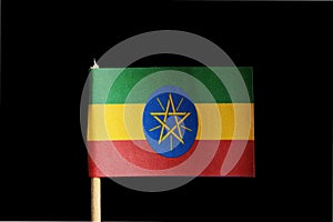 A national flag of Ethiopia on toothpick on black background. Consists of three traditional colours of green, yellow and red and n