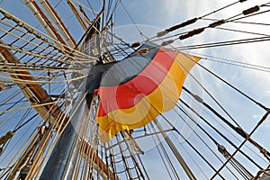 National flag of Germany flutters among ropes of the sailing vessel