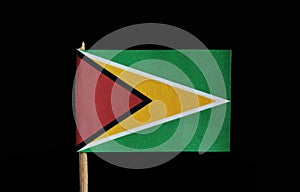 A national flag of Guyana on toothpick on black background. A green field with the black edged red isosceles triangle based on the