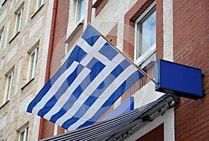 National flag of the Hellenic Republic flutters on a building facade
