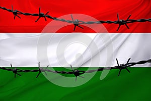 national flag of Hungary on textured background, rows of barbed wire, concept of war, revolution, armed uprising in country,