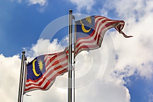 National flag of Malaysia Jalur Gemilang fluttering in the wind against a blue sky with clouds
