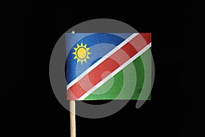 A national flag of Namibia on toothpick on black background. A consists of a white-edged red diagonal band radiating from the lowe