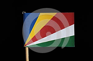 A national flag of Seychelles on toothpick on black background. Consists from five oblique bands of blue, yellow, red, white and g