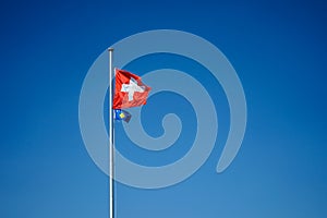 National flag of switzerland and kosova with blue sky background