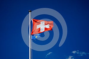 National flag of switzerland and kosova with blue sky background