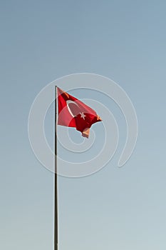 National flag of Turkey featuring white star and crescent waving against blue sky on sunny day