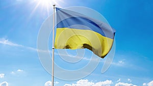 The national flag of Ukraine with blue and yellow stripes flutters in the wind against a blue sunny sky with cumulus clouds and gl