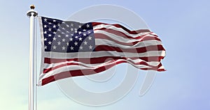 The national flag of the United States of America waving in the wind. Clear sky in the background