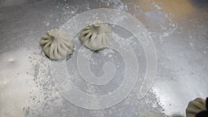 National Georgian cuisine Khinkali. Closeup shot of chef hands putting Dumplings on tray. Lines raw ready-to-cook foods