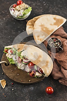 National Greek fast food pita with chicken and fresh vegetables on a wooden Board dark background