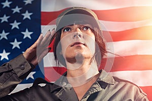 National holidays in the United States. Close up ortrait of a female soldier saluting, against the background of the American flag