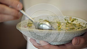 national traditional Russian dish - okroshka on a plate spinning on a wooden background.