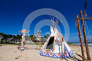 Native american indian tepee and totem pole on the beach blue sk