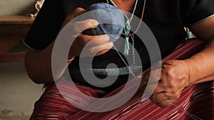 Native Karen Sgaw hill tribe woman rolling a ball of blue dyed thread in preparation for hand weaving traditional clothing and cra