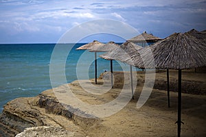 Native umbrellas are alligned and putted in the cliff of the beach. The water is so beautiful and so blue. Use to shade tourist wh