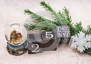 Nativity scene about the Birth of Jesus Christ in a glass ball. Calendar cubes and spruce branches on a gray background. Christmas