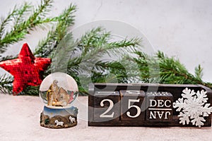 Nativity scene about the Birth of Jesus Christ in a glass ball. Calendar cubes and spruce branches on a gray background. Christmas