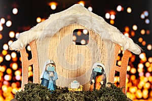 Nativity scene portal with figurines with face masks on a background of defocused lights