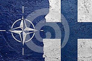 NATO and Finland - Cracked concrete wall painted with a OTAN flag on the left and a finlandian flag on the right stock photo