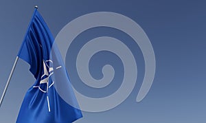 NATO flag on flagpole on blue background. Place for text. The flag is unfurling in wind. North Atlantic Alliance. Europe. 3D