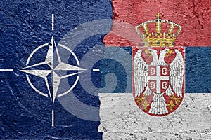 NATO and Serbia - Cracked concrete wall painted with a OTAN flag on the left and a Serbian flag on the right stock photo