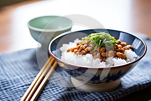 natto atop a bed of steamed white rice in a bowl