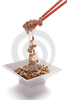 Natto, Fermented Japanese Soybeans, Falling From Chopsticks on White Background