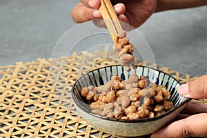 Natto in a Plate on Cement Background Lifted with Chopsticks