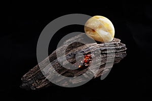 Natural amber. A piece of yellow opaque natural amber on large piece of dark stoned wood.