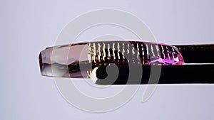 natural ametrine in the tweezers on the background