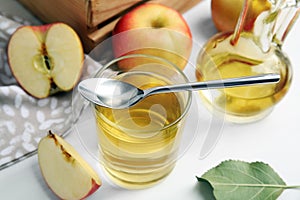 Natural apple vinegar and fresh fruits on white wooden table