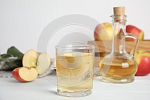 Natural apple vinegar and fresh fruits on white wooden table