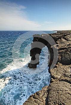 Natural arch in the black lava rock cliffs